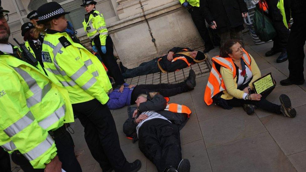 Detained activists with police near the cenotaph monument