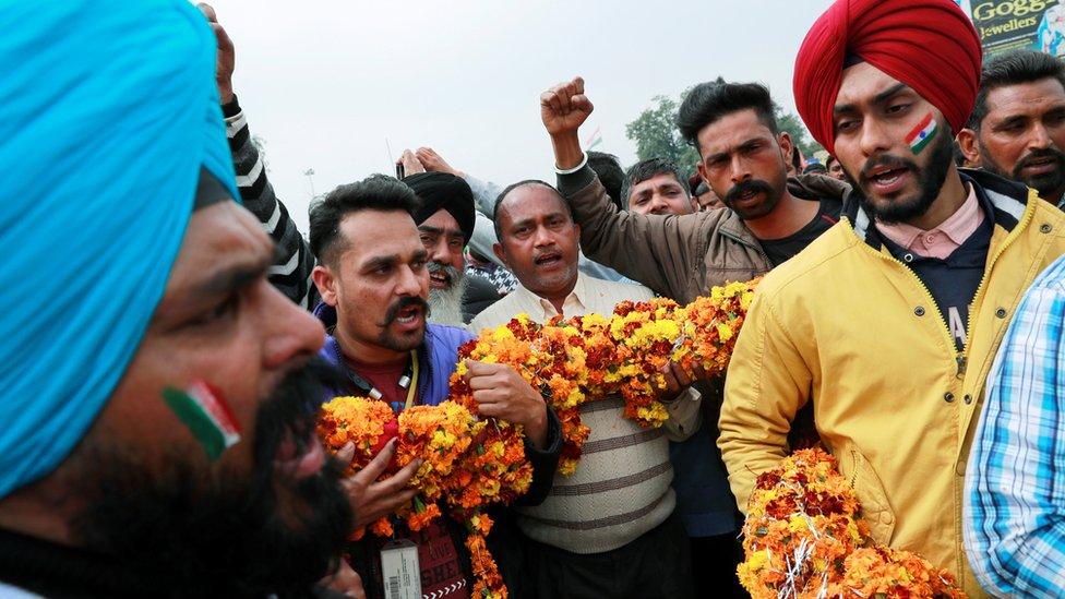 People hold a garland as they shout patriotic slogans before the arrival of Indian Air Force pilot, who was captured by Pakistan on Wednesday, near Wagah border, on the outskirts of the northern city of Amritsar, India, March 1, 2019