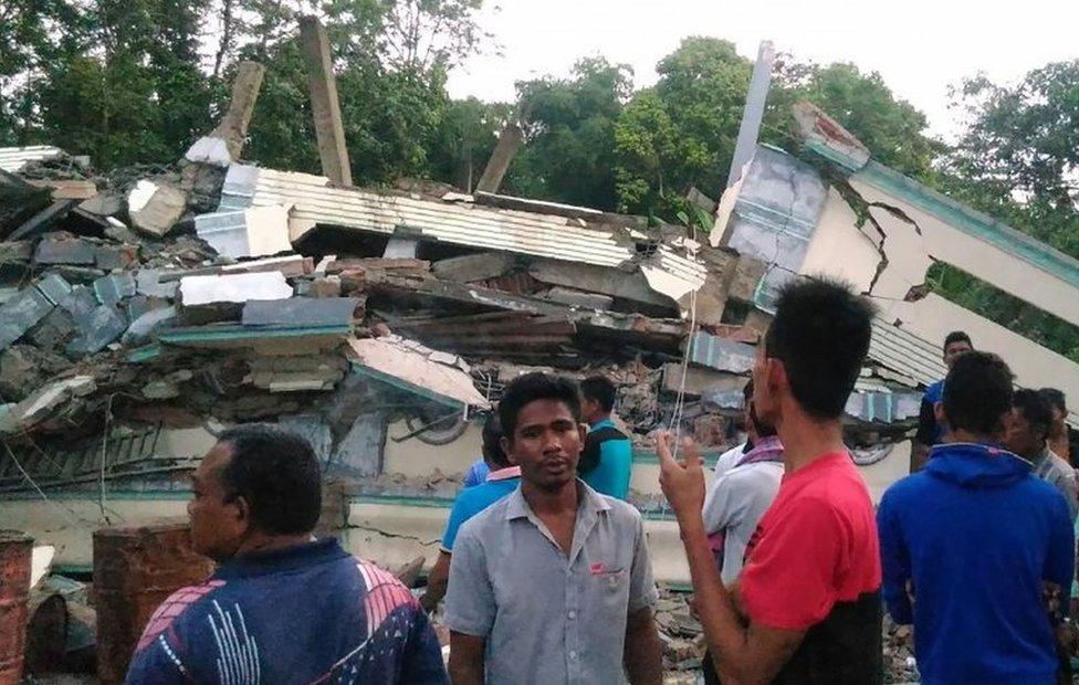 Residents gather around a collapsed building after a 6.5-magnitude earthquake struck the town of Pidie, Indonesia's Aceh province in northern Sumatra, on December 7, 2016.