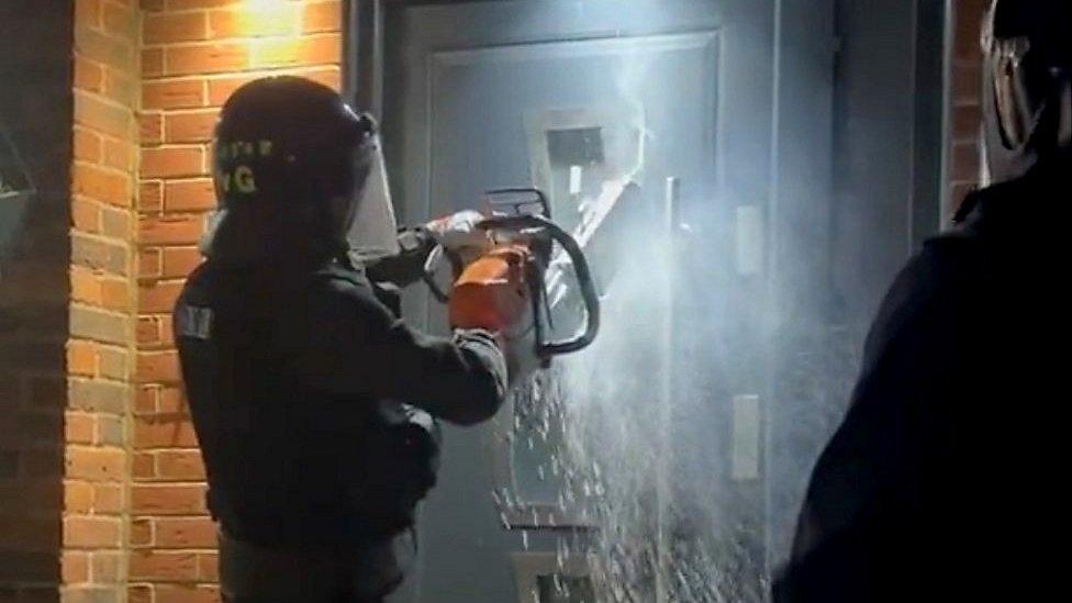 Essex Police use a chainsaw to cut through a door during a raid