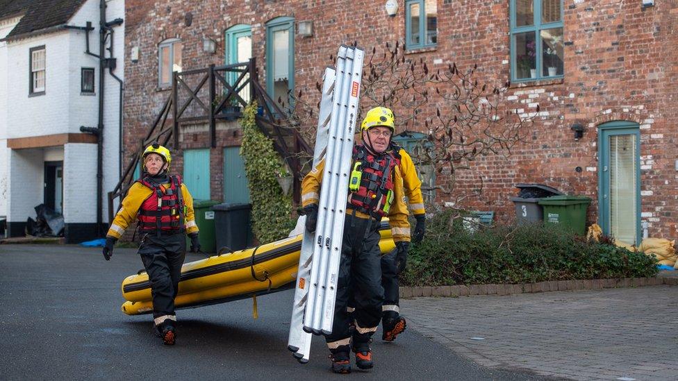 Fire and Rescue officers carry ladders and an inflatable raft in Bewdley, Worcestershire,