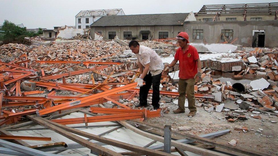 Two workers collect metal girders left over from demolished factories in Zhoupu Township in Pudong district of Shanghai, 7 June 2016.