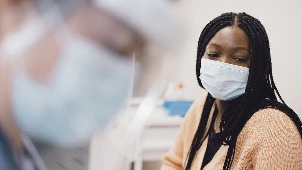 A woman wearing a mask in a medical setting