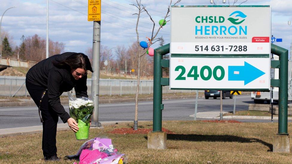 A woman places flowers outside Residence Herron, a care facility where 31 people have died