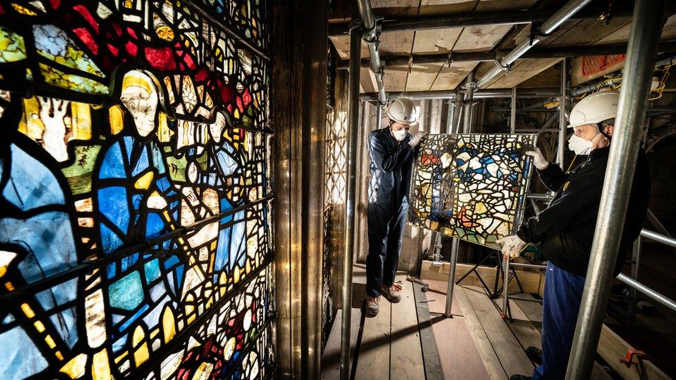 Workers with the window panels and scaffolding