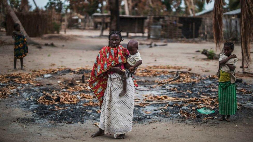 Woman and child amid burned buildings