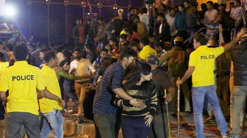 Man helps a woman during unrest in Bangalore (31 Dec 2016)