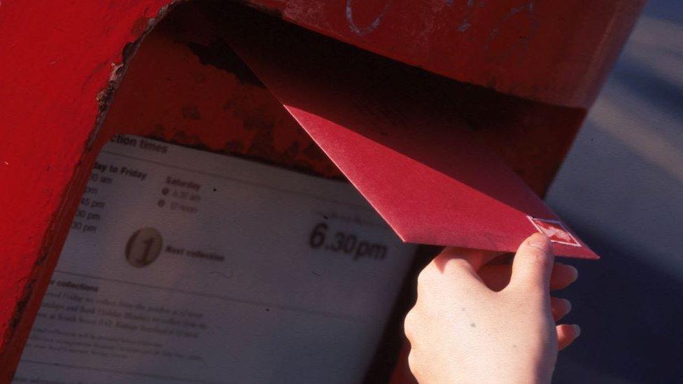 Person putting letter into a postbox