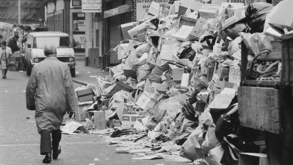 A man walking past a pile of rubbish in London in February 1979