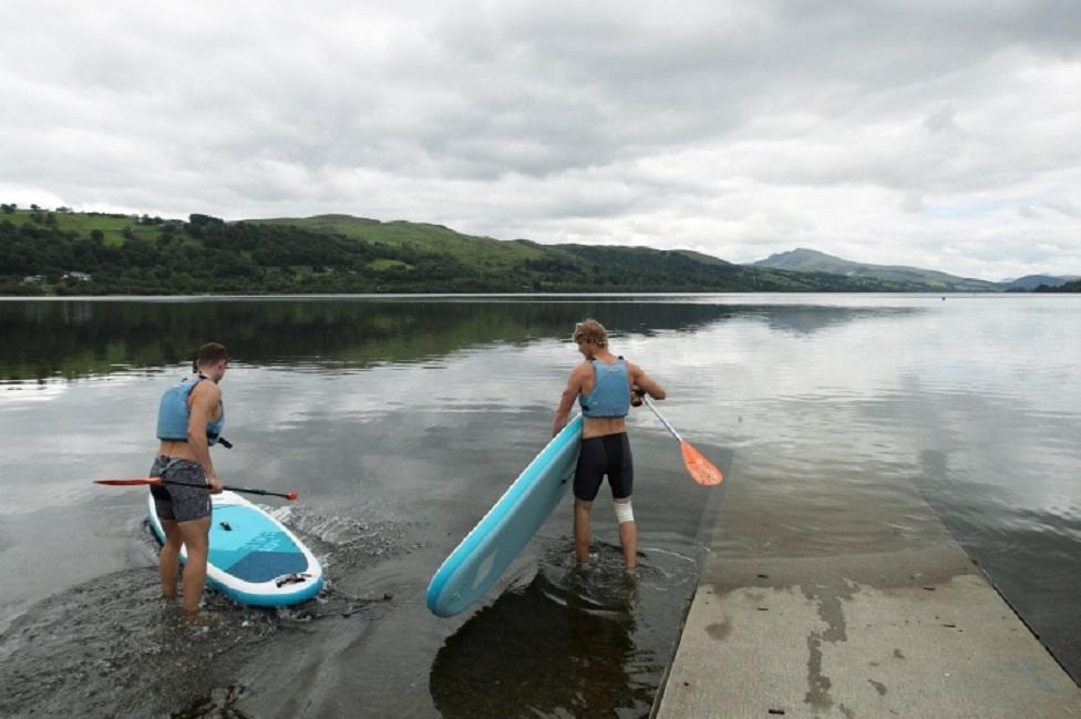 Men wearing life vests get ready with their paddle boards as the Bala Adventure and Watersports Centre in Bala, Gwynedd