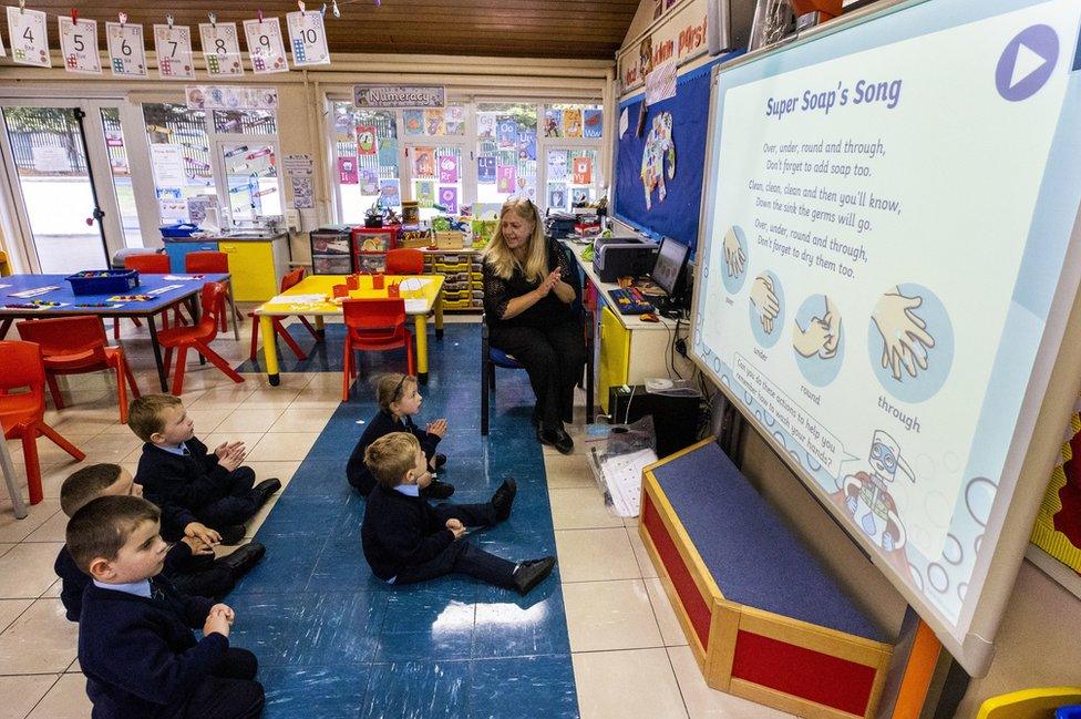 A teacher and young schoolchildren in a classroom