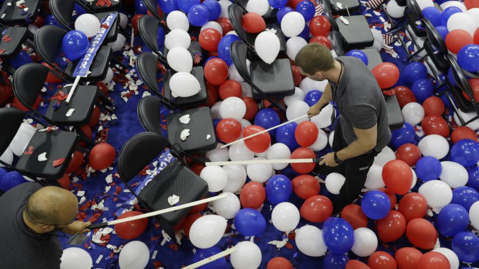 Workers pop balloons during cleanup after the final day of the Democratic National Convention