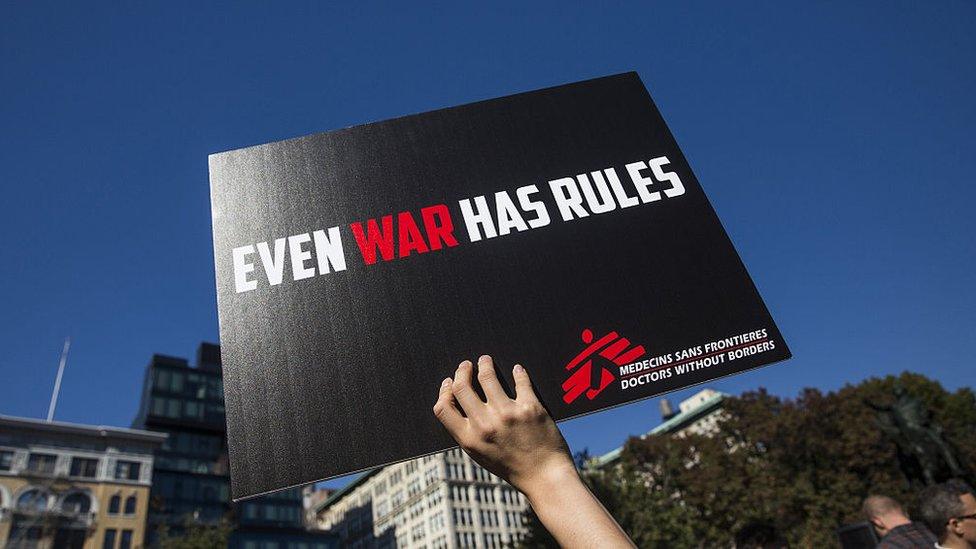 A placard reading "Even war has rules"