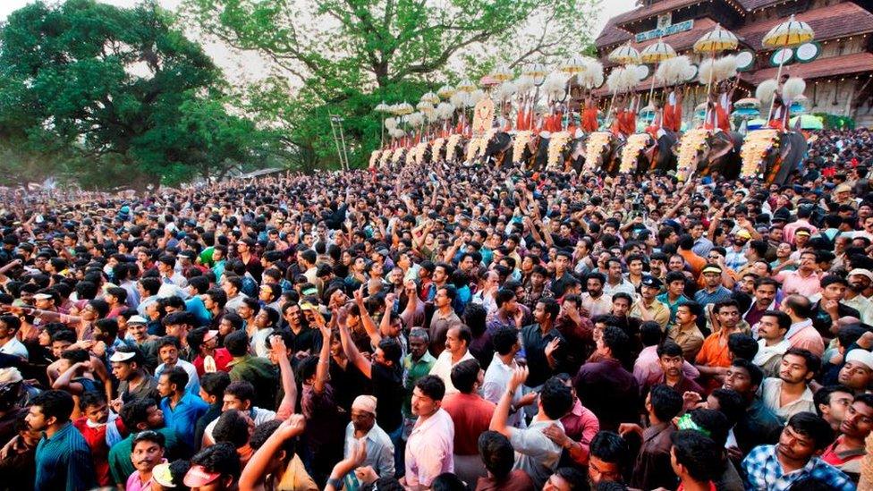 Thousands gathers before a temple in Kerala. Ceremonial elephants can be seen in the background.