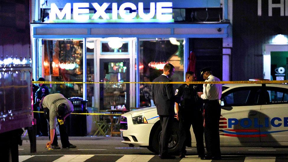 Police officers stand outside a restaurant after a shooting in Washington, DC, on July 22, 2021