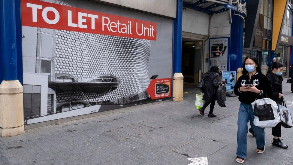 A woman walking past a closed down shop