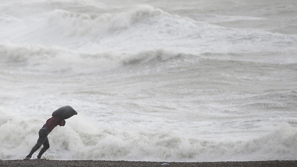 A man leans into the wind on the beach at Newhaven, southern England