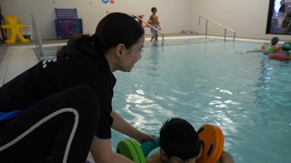 Marta Hulin helps a young swimmer