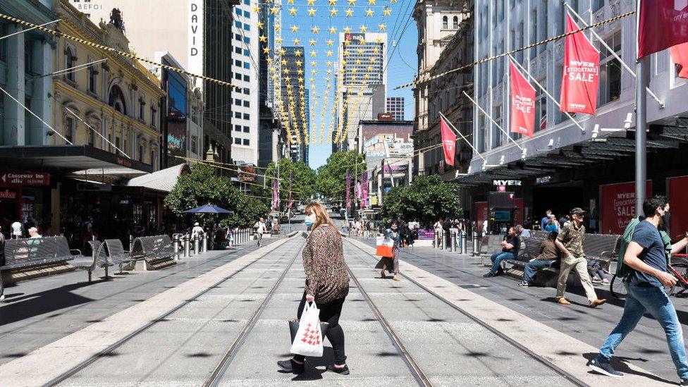 Shoppers wearing masks cross Bourke Street Mall in central Melbourne on Boxing Day 2020