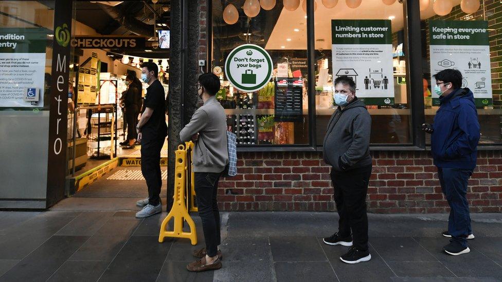 Queue of shoppers socially distance while waiting to enter a supermarket store