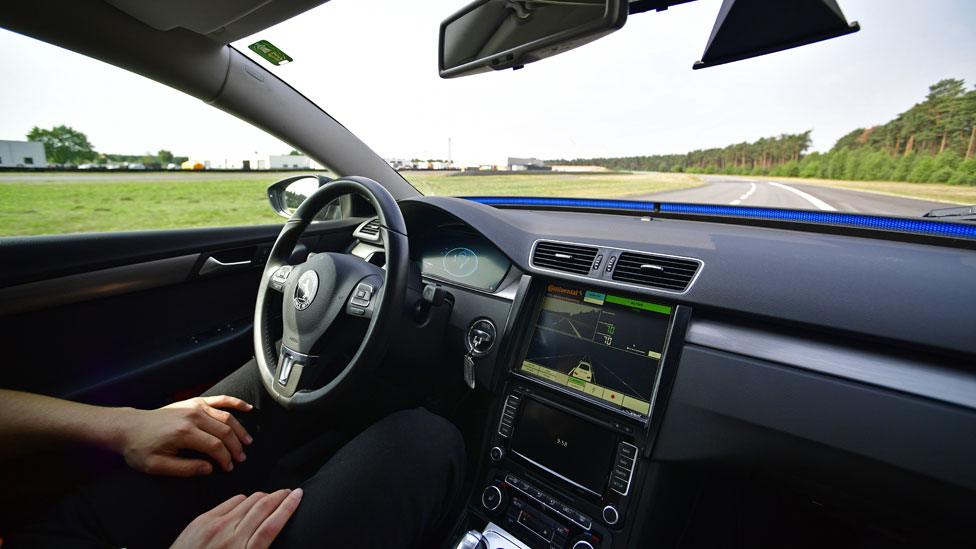 Car driving itself, with man in driver seat doing nothing