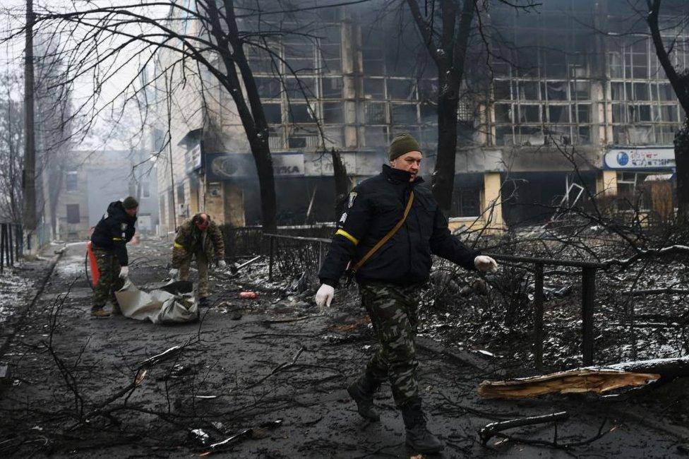 Police officers remove the body of a passerby killed in yesterday's airstrike that hit Kyiv's main television tower in Kyiv on March 2, 2022.