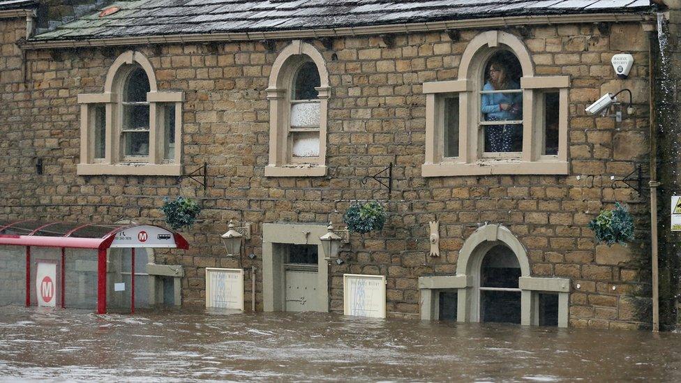 People look out from their windows and are trapped by flood water as the River Calder bursts its bank's in Mytholmroyd, England.