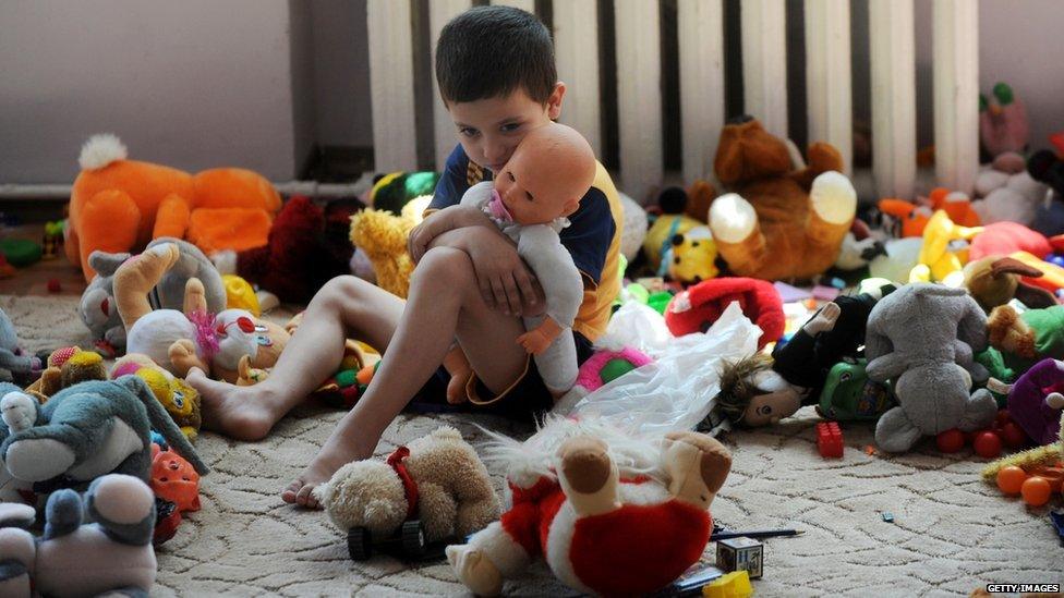 A young boy cuddling a doll