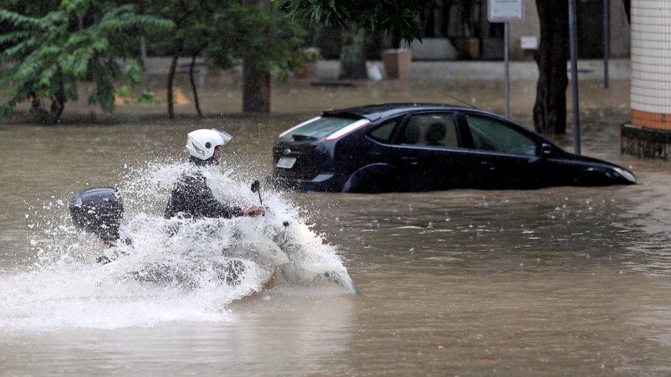 A man drives his motorcycle through flood waters