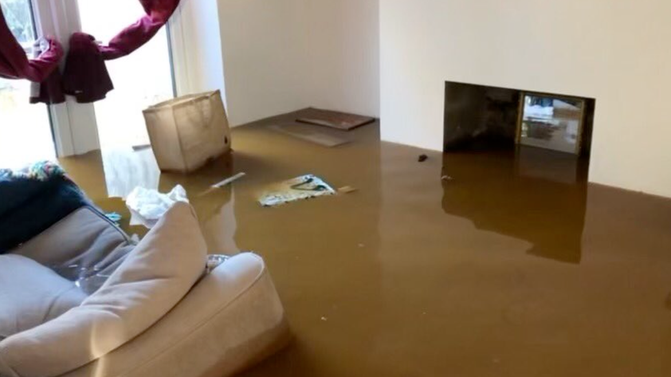 In one home floodwater can be seen filling the living room