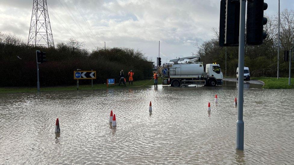 A flooded roundabout with people working on it