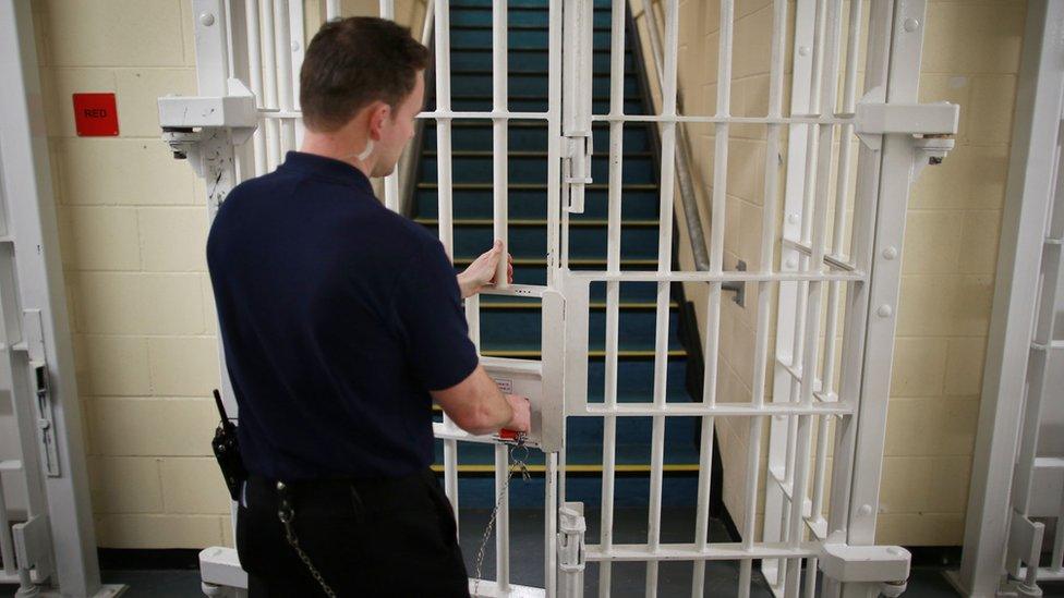 A prison officer opening a gate