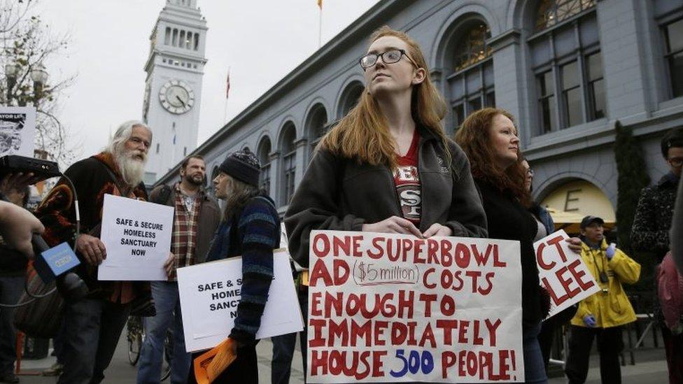 Meg Bender holds up a sign outside the Ferry Building during a protest to demand city officials do more to help homeless people outside Super Bowl City, a pro-football"s weeklong theme park near the famed Ferry Building in San Francisco on 3 February 2016.