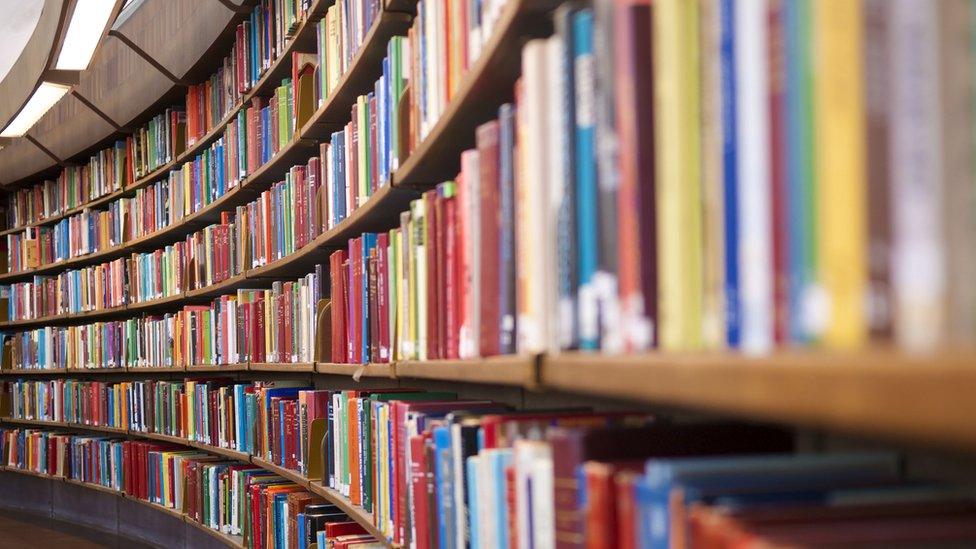 A long curved library bookshelf stacked with books