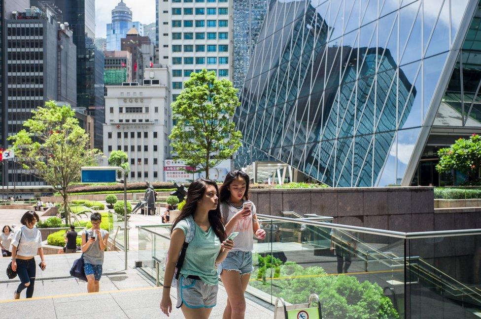 Two girls use their phones in the Central district of Hong Kong on July 26, 2016.