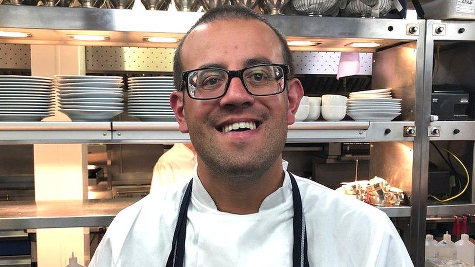 A man smiling in a restaurant kitchen