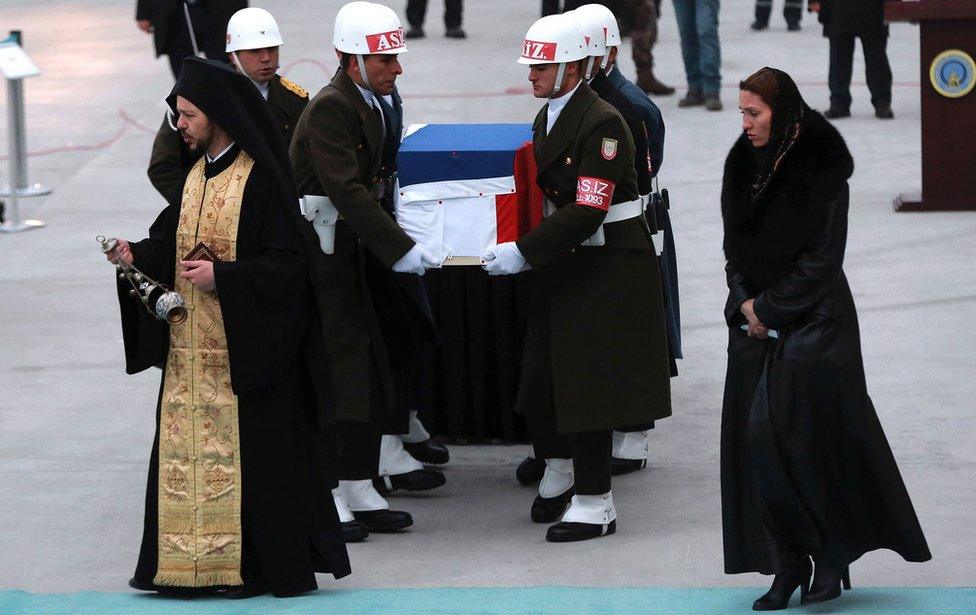 An orthodox clergyman prays next to the flag-wrapped coffin of late Russian Ambassador to Turkey Andrei Karlov during a ceremony at Esenboga airport in Ankara, Turkey