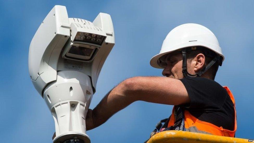 A worker installs a surveillance camera in the Eurotunnel site, to prevent the migrants to enter, in Coquelles near Calais