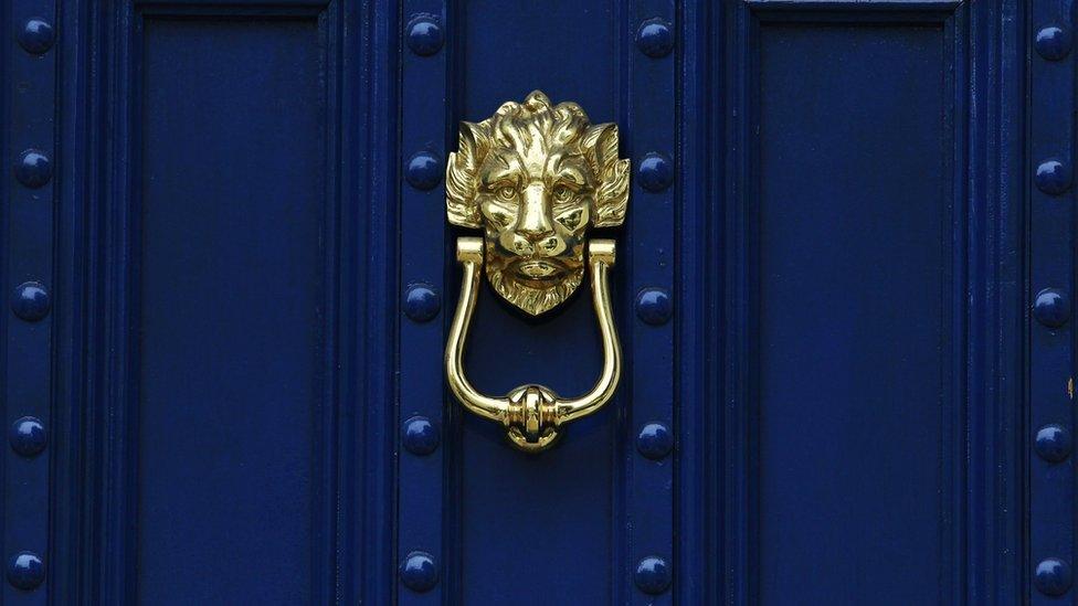 A brass door knocker is pictured on a blue door in London