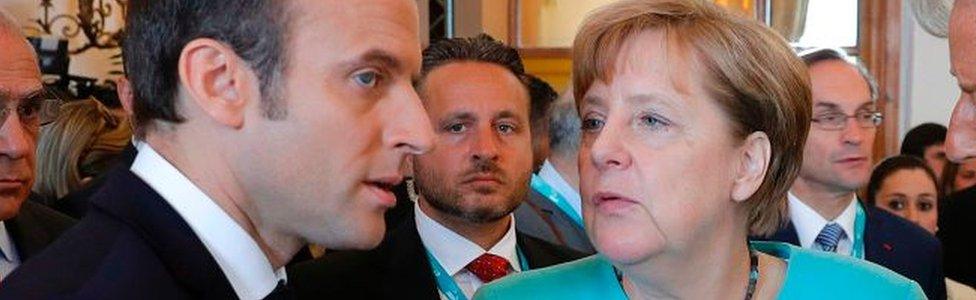 French President Emmanuel Macron (L) speaks with German Chancellor Angela Merkel as they attend a G7 expanded session during the G7 Summit in Taormina, Sicily, on 27 May 2017