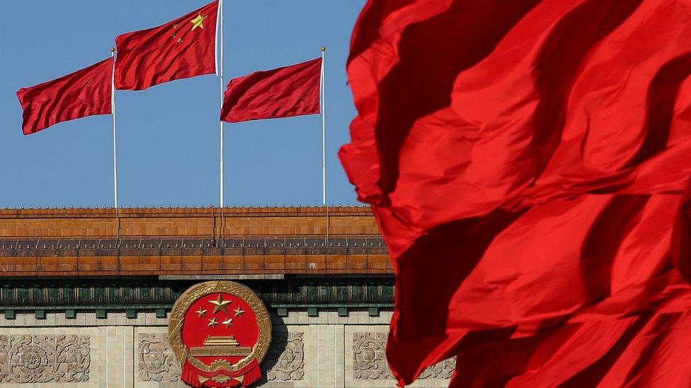 photograph shows the chinese flag waving outside the Great Hall of the People in Beijing