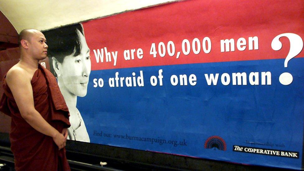 A Burmese monk looks at a poster of Myanmar's pro-democracy leader Aung San Suu Kyi in London in June 1