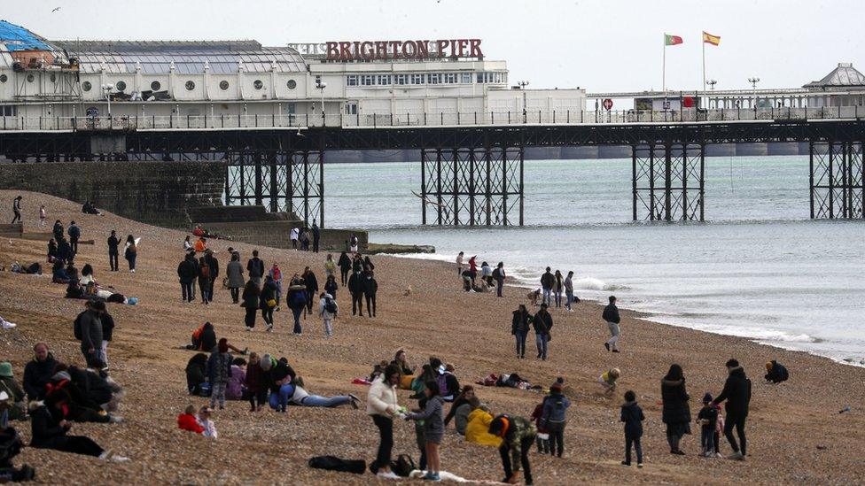 People sit on Brighton beach, East Sussex. Picture date: Friday April 2, 2021.