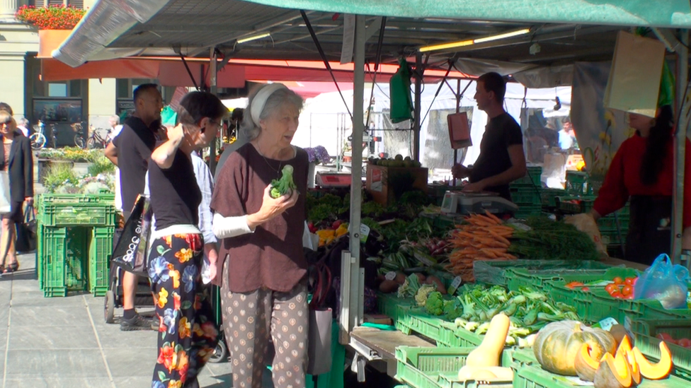 A number of people examine fresh produce at a farmer's market