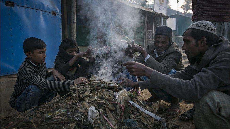 Rohingya refugees warm themselves by a fire in a refugee camp on December 12, 2019 in Cox's Bazar, Bangladesh