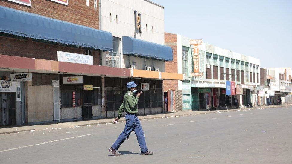 A woman walks on a deserted street with closed shops, a day before anti government protests, in the central business district of Harare, Zimbabwe, 30 July 2020.