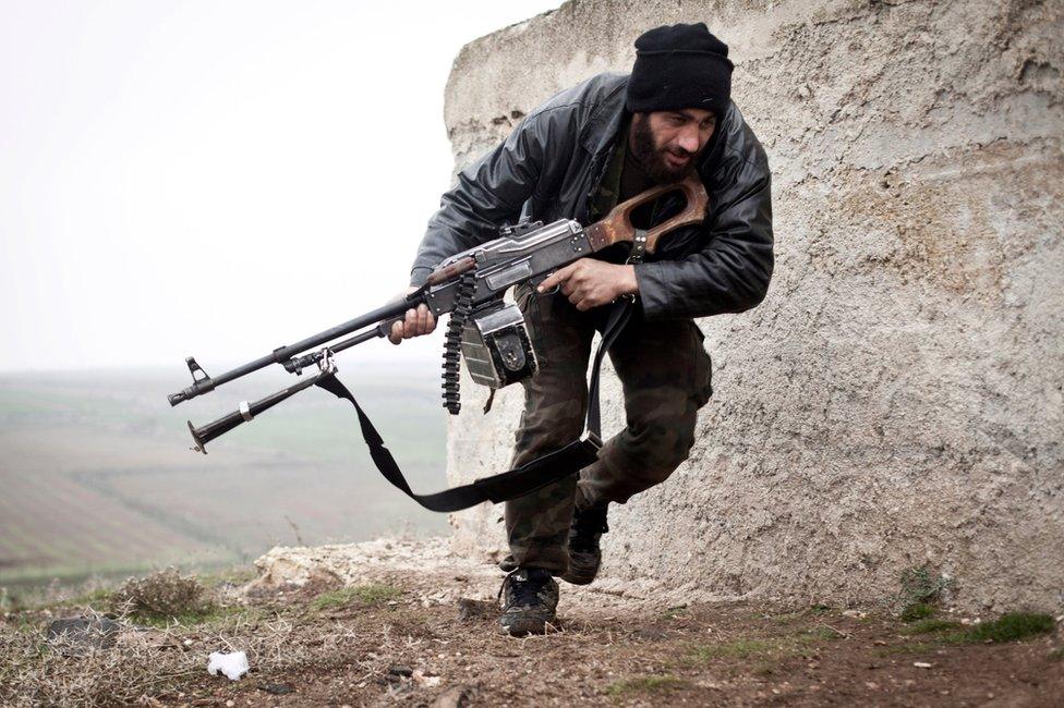 Syrian rebel takes cover during fighting with the Syrian army in Azaz, Syria (17 December 2012)