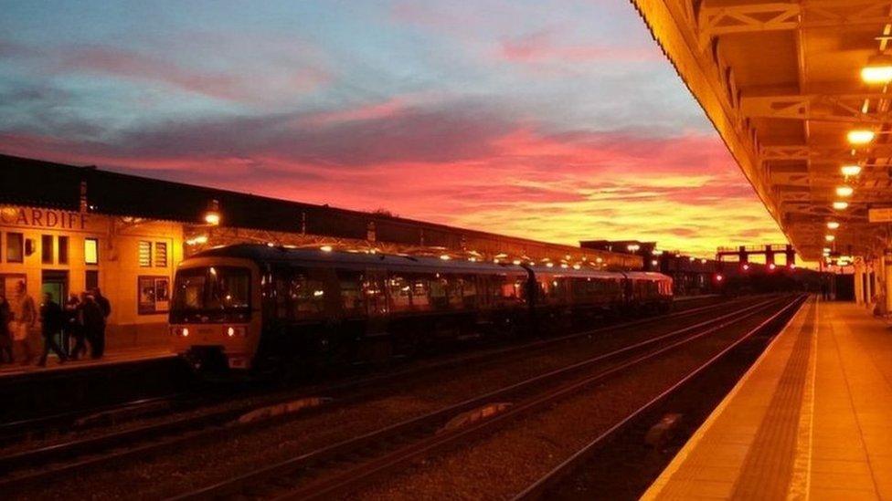 Tren yn cyrraedd gorsaf Caerdydd dan y machlud