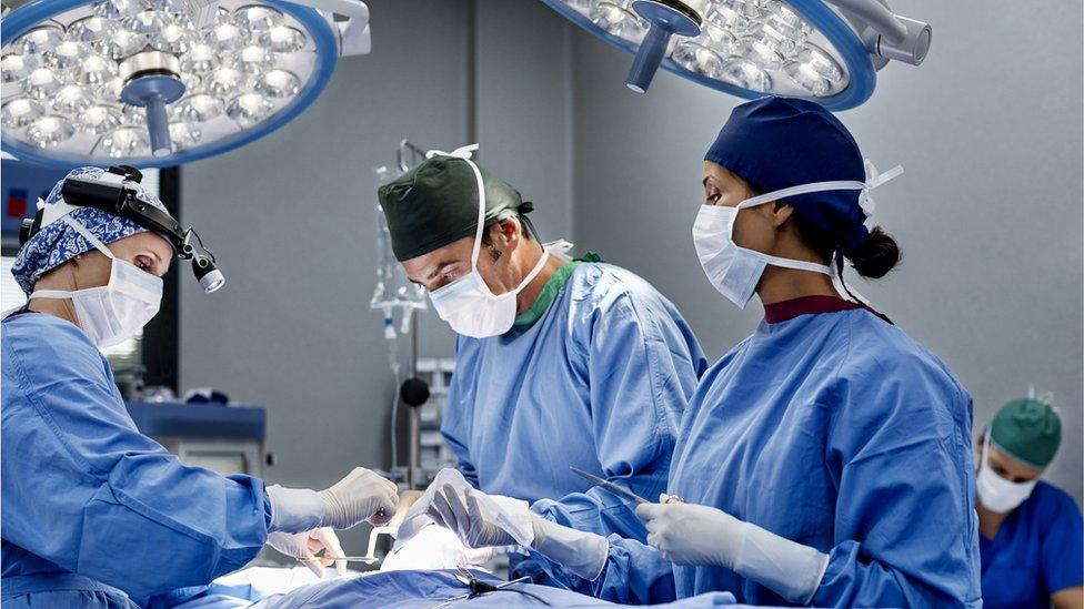 Female surgeon operating patient at table. Medical professionals are working in emergency room. They are wearing scrubs.