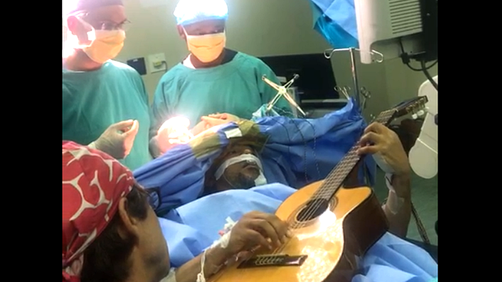 Musa Manzini plays his guitar on the operating table